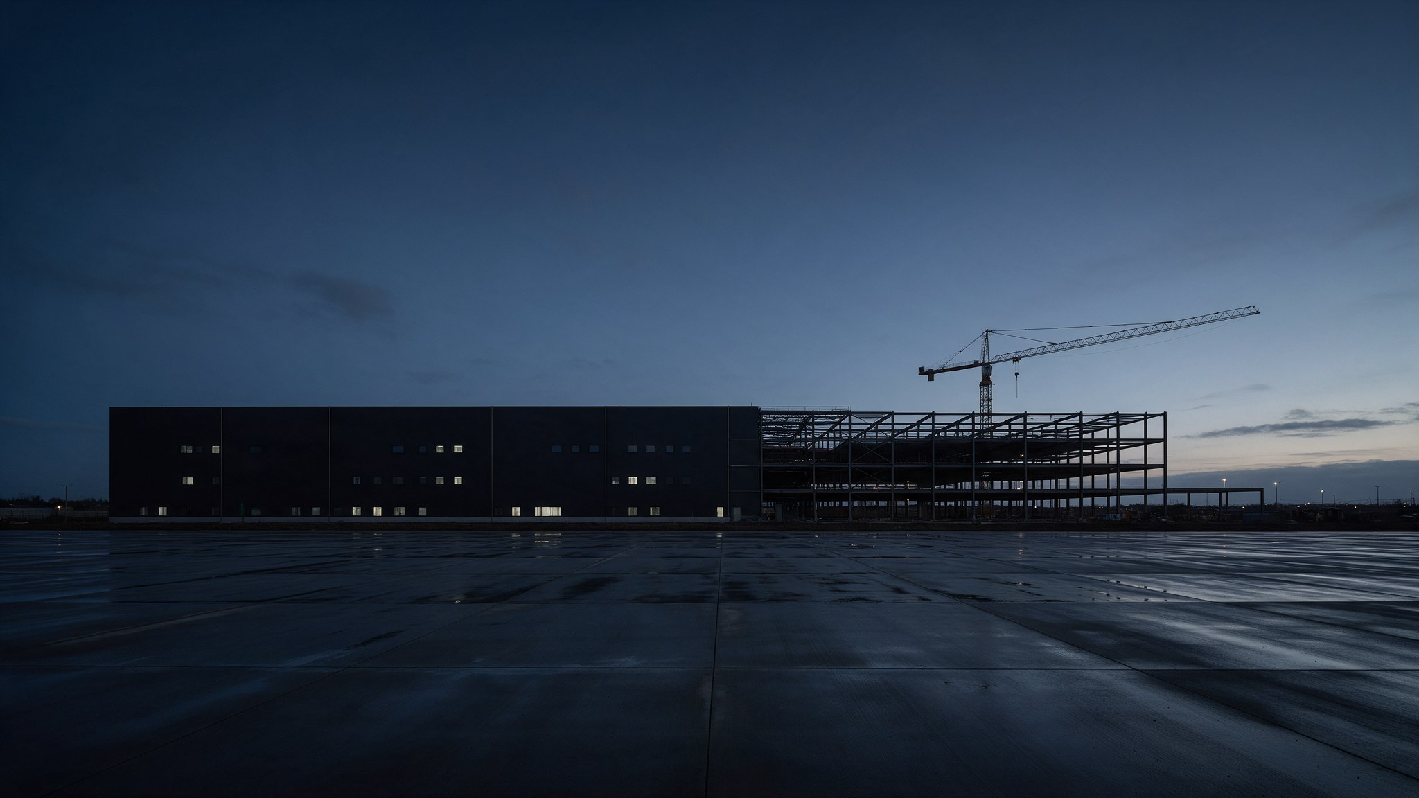 Data center shell under construction at dusk, with a crane over the steel frame