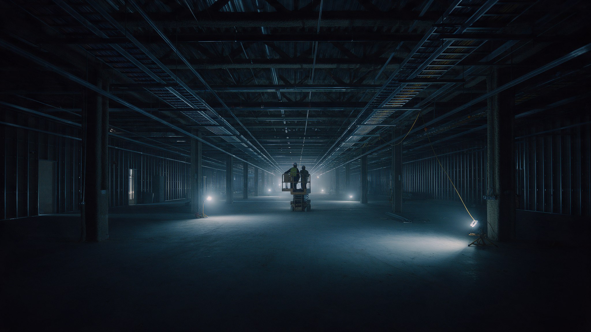 Empty data hall under construction, with a worker in the distance